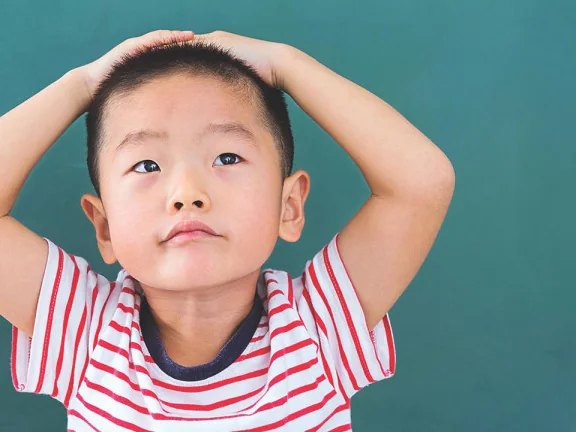 A young boy with his hands on his head, looking up. He said “monkeys!”, the app heard “recipes”, so he asked “Where are the monkeys?”